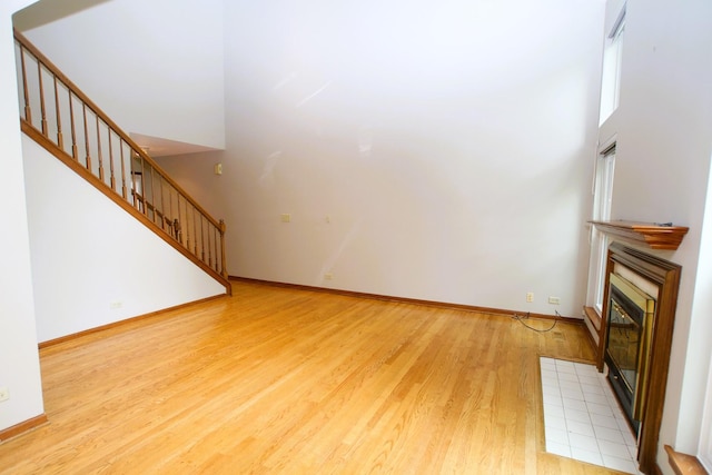 176 Millers Xing, Itasca, IL 60143 - unfurnished living room with light wood-style floors, a fireplace with flush hearth, stairs, and baseboards