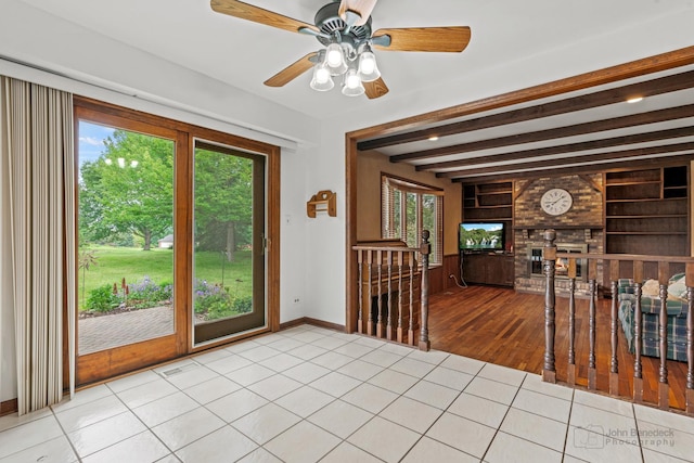 19N050 Felsmith Rd, Hampshire, IL 60140 - tiled empty room with plenty of natural light, built in shelves, beamed ceiling, a ceiling fan, and a fireplace