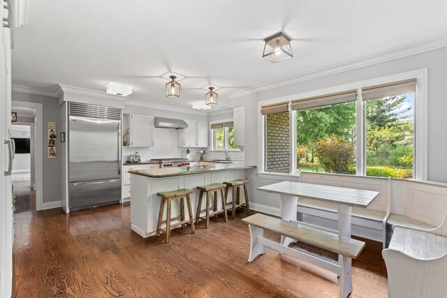2510 Marian Ln, Wilmette, IL 60091 - kitchen featuring built in refrigerator, a peninsula, wall chimney range hood, decorative backsplash, and white cabinets