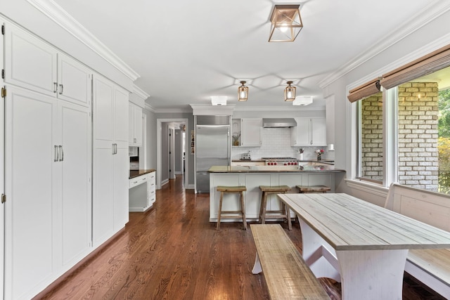 2510 Marian Ln, Wilmette, IL 60091 - kitchen featuring built in fridge, wall chimney exhaust hood, white cabinets, backsplash, and a peninsula