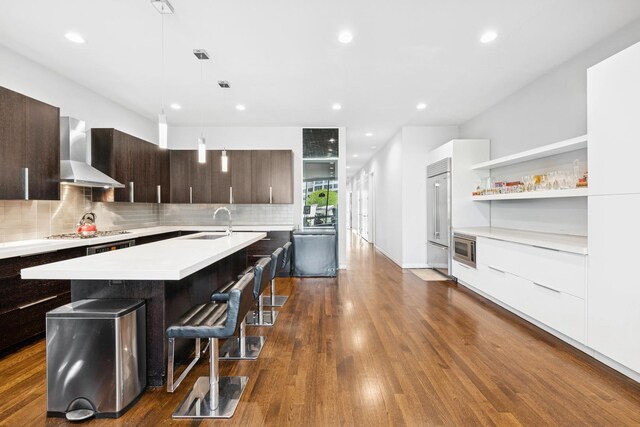 919 N Larrabee St Unit 3N, Chicago, IL 60610 - kitchen with wall chimney exhaust hood, modern cabinets, light countertops, a sink, and an island with sink