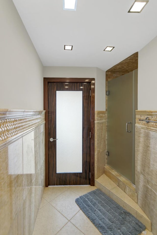 111 E Chestnut St Unit 24C, Chicago, IL 60611 - bathroom featuring tile patterned flooring, a shower stall, tile walls, and a wainscoted wall