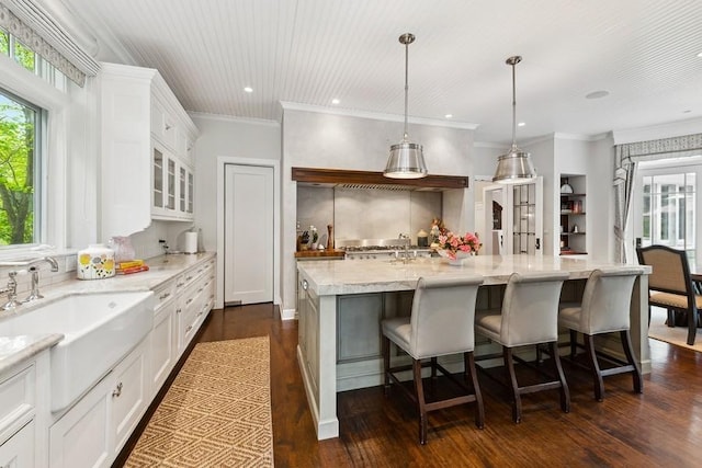kitchen featuring white cabinets, dark wood-type flooring, tasteful backsplash, glass insert cabinets, and a breakfast bar