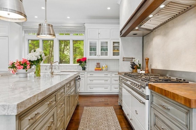 kitchen featuring wall chimney exhaust hood, dark wood finished floors, an island with sink, white cabinets, and recessed lighting