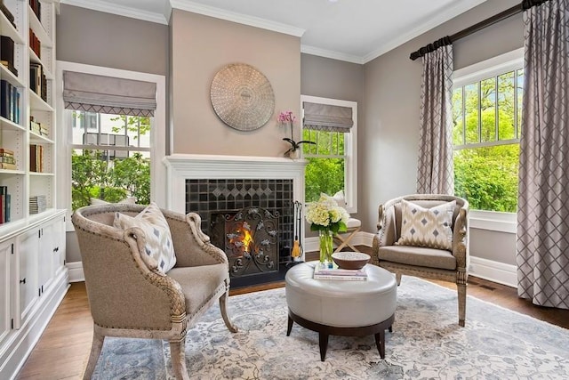 living area with ornamental molding, wood finished floors, plenty of natural light, and a tile fireplace