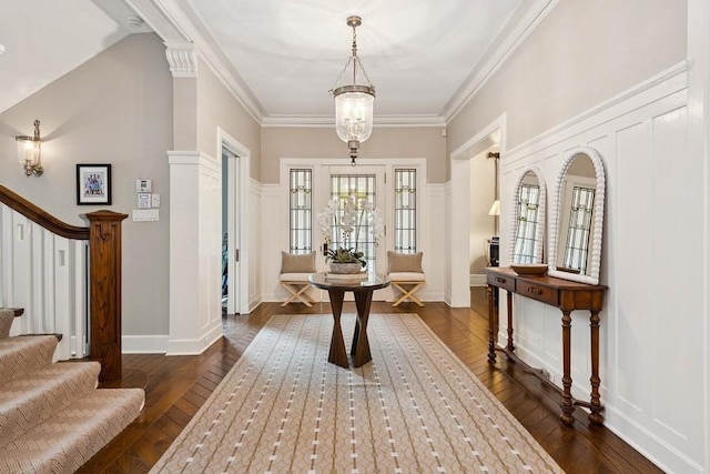 entrance foyer with stairs, dark wood finished floors, ornamental molding, and a chandelier
