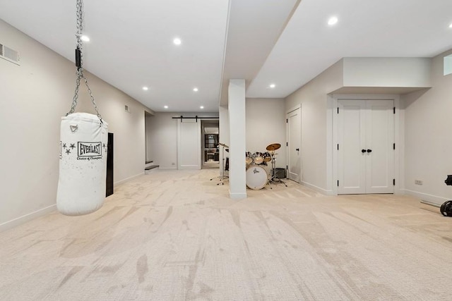 finished below grade area featuring a barn door, recessed lighting, and light carpet