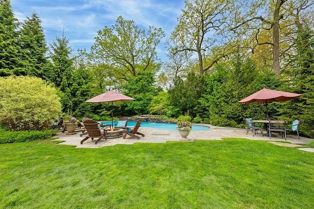outdoor pool with a patio, a lawn, and a fire pit