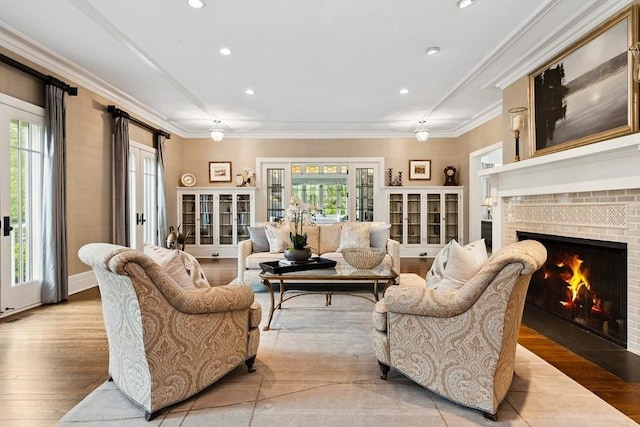 living room with a brick fireplace, healthy amount of natural light, light wood-style flooring, crown molding, and recessed lighting