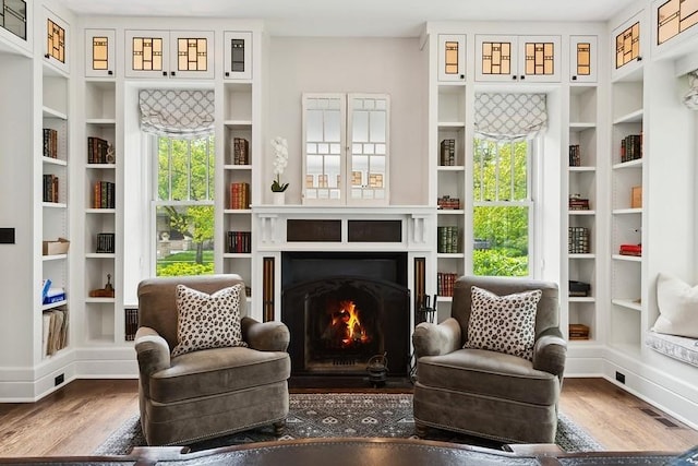 living area with wood finished floors and a fireplace with flush hearth