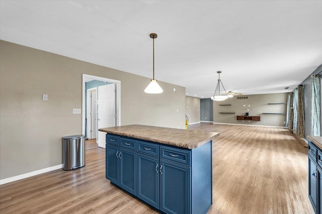 2302 Slade Ln, Mahomet, IL 61853 - kitchen featuring blue cabinets, light wood finished floors, pendant lighting, open floor plan, and a center island