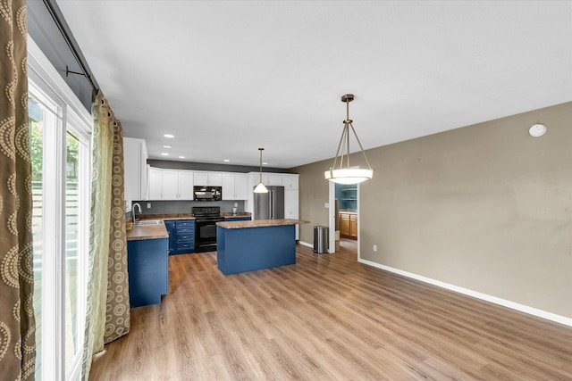 2302 Slade Ln, Mahomet, IL 61853 - kitchen featuring black appliances, light wood-type flooring, a center island, white cabinets, and hanging light fixtures