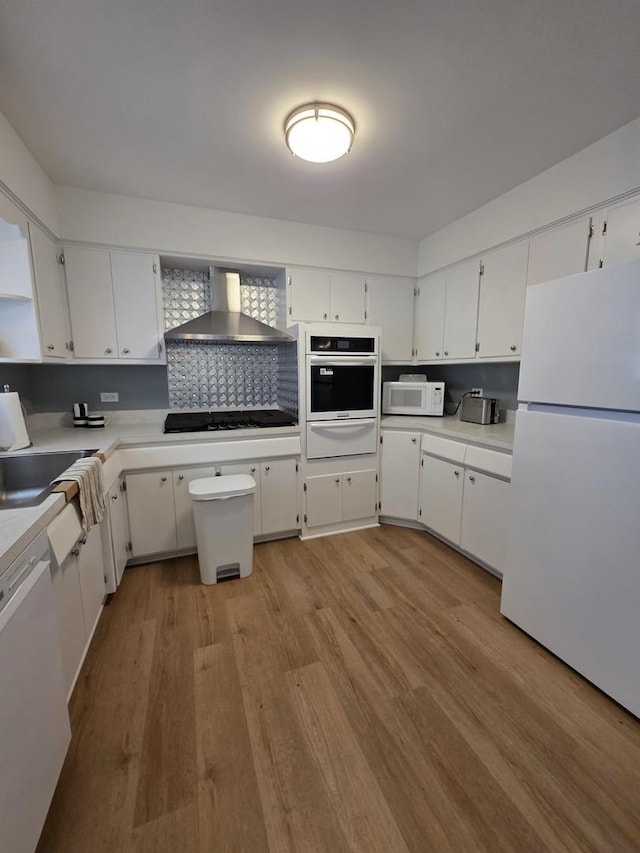 6124 W Berteau Ave, Chicago, IL 60634 - kitchen featuring white appliances, a warming drawer, wall chimney exhaust hood, light wood-type flooring, and white cabinetry