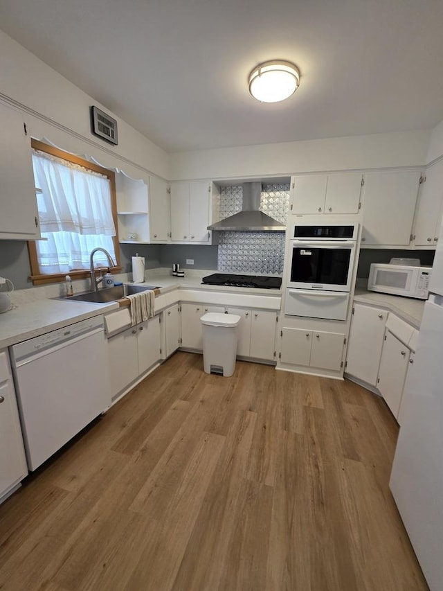 6124 W Berteau Ave, Chicago, IL 60634 - kitchen featuring white appliances, wall chimney range hood, a warming drawer, light wood-type flooring, and a sink