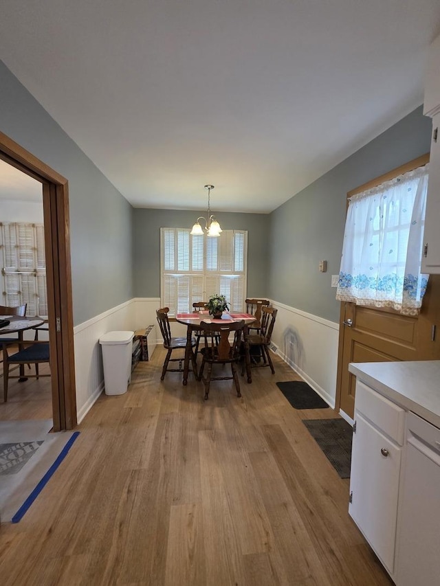 6124 W Berteau Ave, Chicago, IL 60634 - dining space featuring wainscoting, light wood-type flooring, and a chandelier
