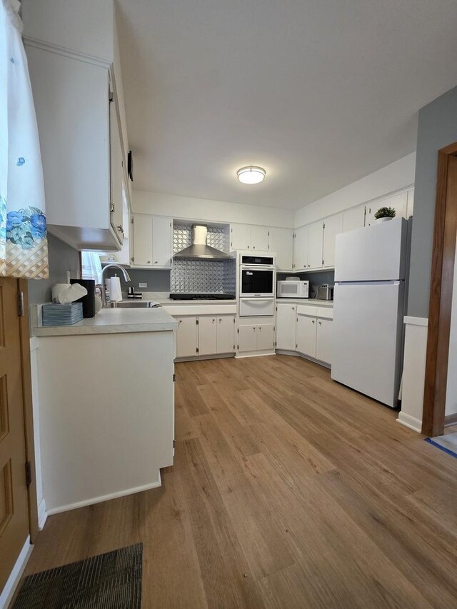 6124 W Berteau Ave, Chicago, IL 60634 - kitchen featuring white appliances, a warming drawer, a sink, light wood-type flooring, and white cabinetry