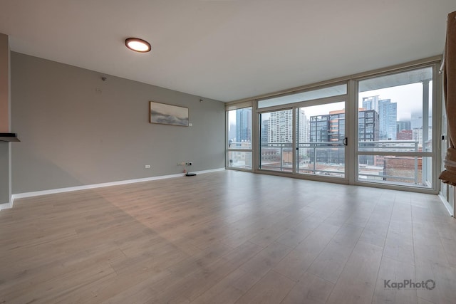 757 N Orleans St Unit 1104, Chicago, IL 60654 - spare room with a city view, a wall of windows, light wood-style floors, and baseboards