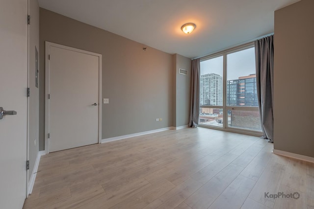 757 N Orleans St Unit 1104, Chicago, IL 60654 - unfurnished room featuring a wall of windows, light wood finished floors, and baseboards