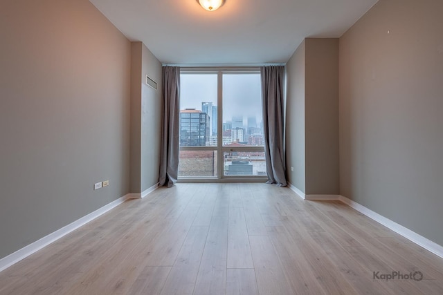 757 N Orleans St Unit 1104, Chicago, IL 60654 - spare room with a wall of windows, light wood-style flooring, baseboards, and a city view