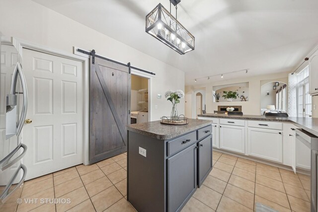 25338 Scott Dr, Plainfield, IL 60544 - kitchen featuring light tile patterned flooring, a barn door, arched walkways, white cabinetry, and dark countertops
