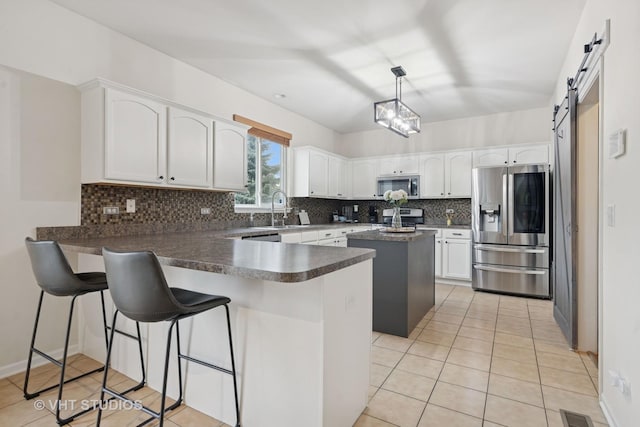 25338 Scott Dr, Plainfield, IL 60544 - kitchen featuring stainless steel appliances, a peninsula, a barn door, tasteful backsplash, and light tile patterned flooring