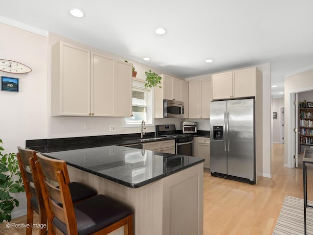 840 N Wood St Unit 2, Chicago, IL 60622 - kitchen featuring appliances with stainless steel finishes, a peninsula, light wood-style floors, dark stone counters, and a kitchen bar