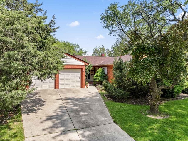 137 N Clark Dr, Palatine, IL 60074 - view of front facade featuring a garage, concrete driveway, brick siding, a chimney, and a front lawn