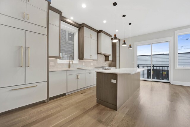 2353 W Ohio St, Chicago, IL 60612 - kitchen featuring a sink, paneled fridge, light wood finished floors, a kitchen island, and backsplash
