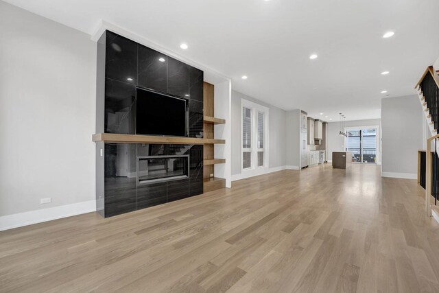 2353 W Ohio St, Chicago, IL 60612 - unfurnished living room featuring a tiled fireplace, light wood-style flooring, stairs, baseboards, and recessed lighting