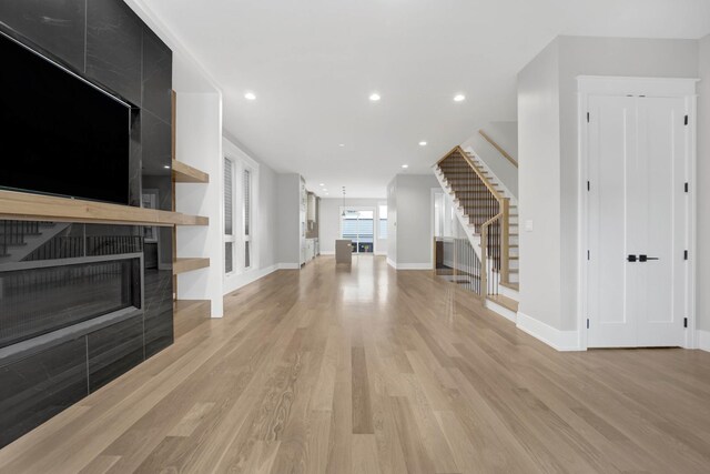 2353 W Ohio St, Chicago, IL 60612 - unfurnished living room with stairs, light wood-style flooring, a tile fireplace, baseboards, and recessed lighting