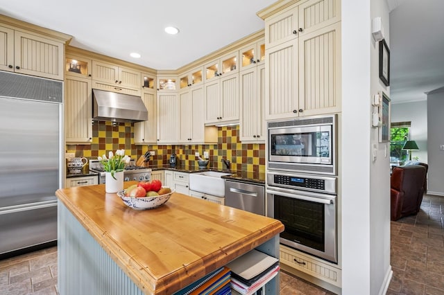 1448 N Mohawk St, Chicago, IL 60610 - kitchen featuring built in appliances, cream cabinets, under cabinet range hood, stone tile floors, and a sink