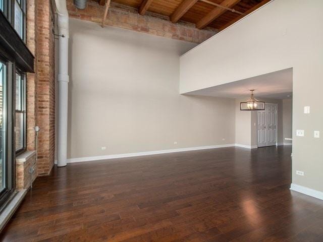 50 E 26th St Unit 406, Chicago, IL 60616 - spare room with a towering ceiling, baseboards, a chandelier, wood finished floors, and wood ceiling with exposed beams