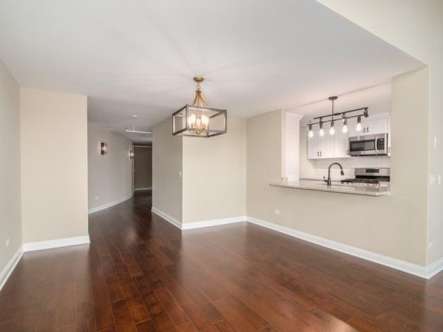 50 E 26th St Unit 406, Chicago, IL 60616 - unfurnished living room featuring dark wood-style floors, a chandelier, baseboards, and a sink