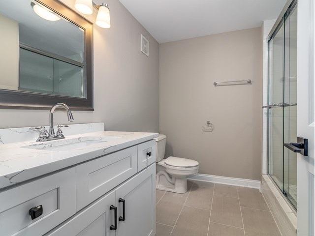 50 E 26th St Unit 406, Chicago, IL 60616 - bathroom with vanity, tile patterned flooring, a shower stall, baseboards, and toilet