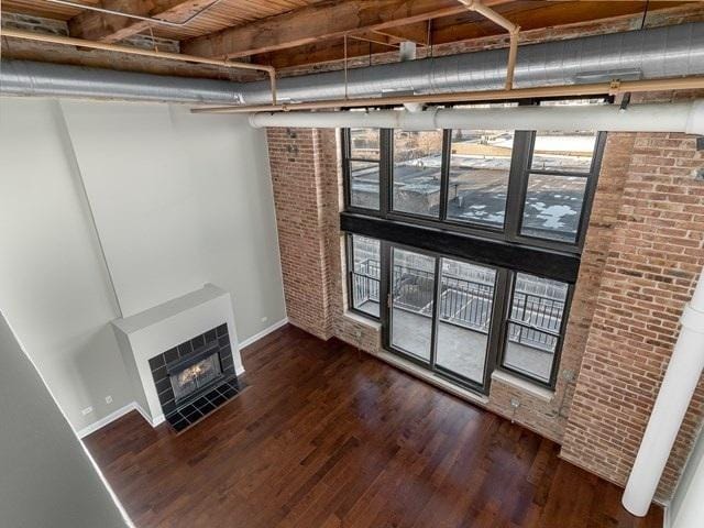 50 E 26th St Unit 406, Chicago, IL 60616 - unfurnished living room featuring brick wall, baseboards, a tiled fireplace, and wood finished floors
