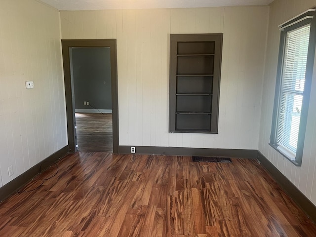 601 15th Ave, Sterling, IL 61081 - empty room with baseboards, wood finished floors, plenty of natural light, built in features, and wooden walls