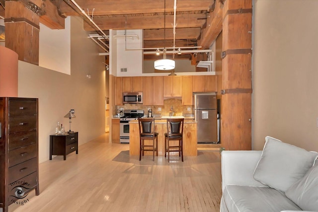 360 W Illinois St Unit 114, Chicago, IL 60654 - kitchen featuring stainless steel appliances, a high ceiling, light wood finished floors, backsplash, and open floor plan