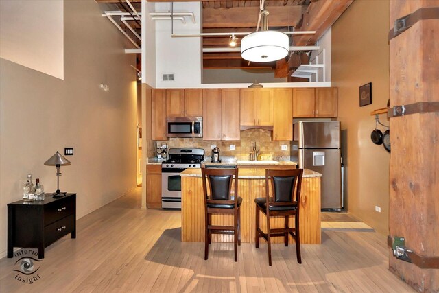 360 W Illinois St Unit 114, Chicago, IL 60654 - kitchen with stainless steel appliances, a towering ceiling, decorative backsplash, light wood-style flooring, and light countertops
