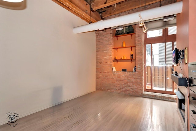 360 W Illinois St Unit 114, Chicago, IL 60654 - unfurnished living room featuring wood finished floors, brick wall, and a towering ceiling