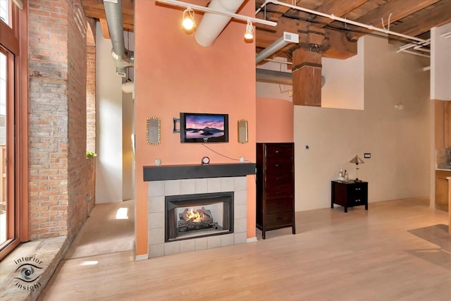360 W Illinois St Unit 114, Chicago, IL 60654 - living room with wood finished floors, a high ceiling, a tile fireplace, and brick wall