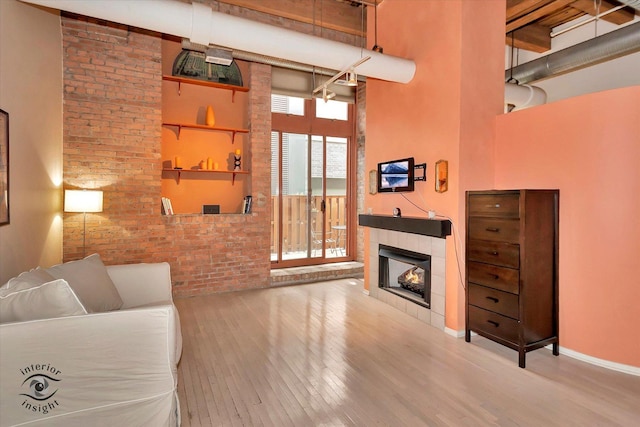 360 W Illinois St Unit 114, Chicago, IL 60654 - living room featuring a tile fireplace, wood finished floors, a towering ceiling, and baseboards