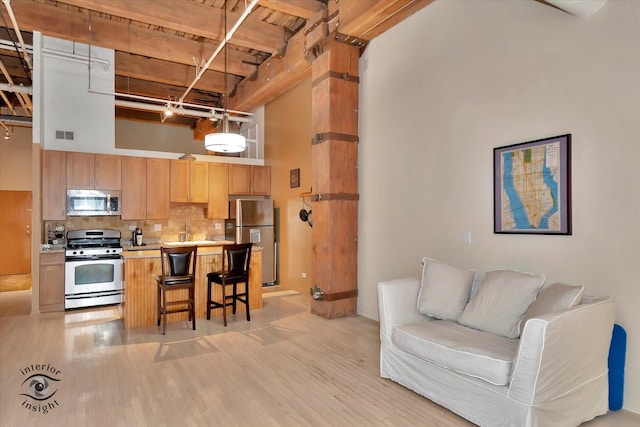 360 W Illinois St Unit 114, Chicago, IL 60654 - kitchen with appliances with stainless steel finishes, light wood-style flooring, a kitchen bar, open floor plan, and a high ceiling