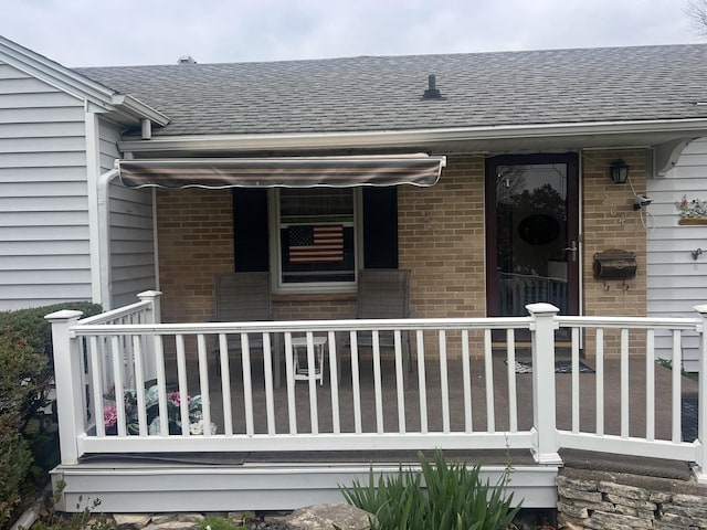 204 Elm St, Morrison, IL 61270 - view of exterior entry featuring brick siding, roof with shingles, and covered porch