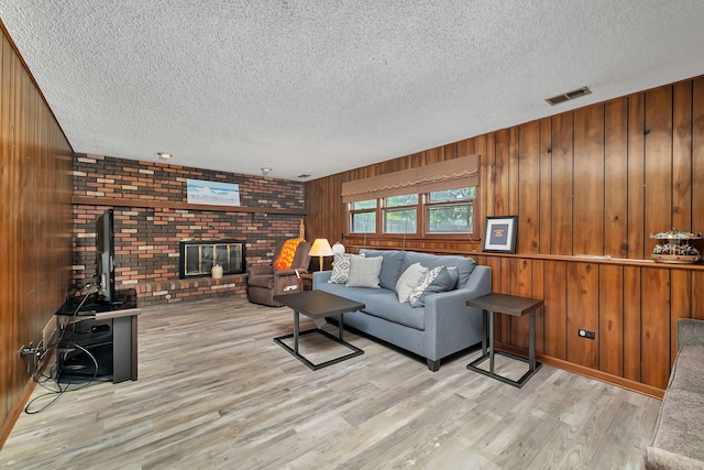 25408 W Willow Dr, Plainfield, IL 60544 - living room featuring a textured ceiling, wood finished floors, wooden walls, and a brick fireplace