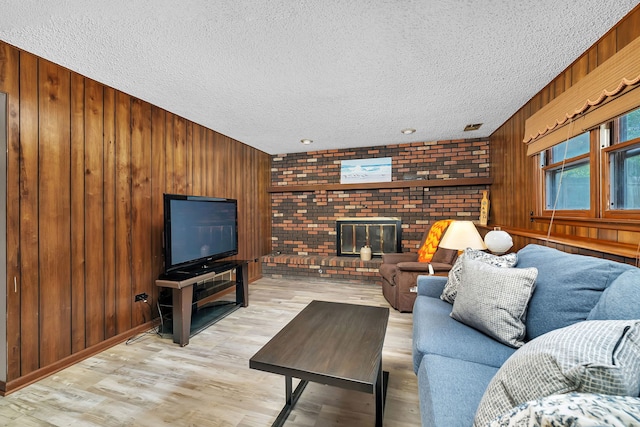 25408 W Willow Dr, Plainfield, IL 60544 - living room featuring a textured ceiling, wooden walls, wood finished floors, and a brick fireplace
