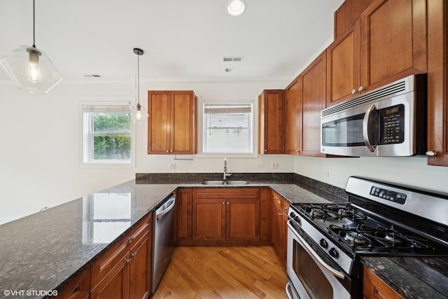3560 S Giles Ave Unit 2, Chicago, IL 60653 - kitchen featuring stainless steel appliances, a sink, crown molding, light wood-style flooring, and decorative light fixtures