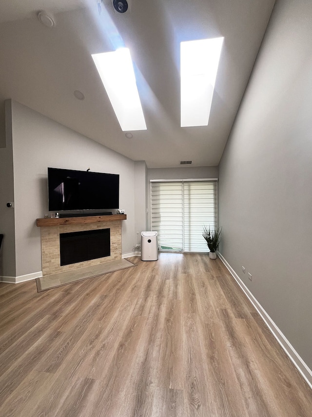 985 W Ct Unit D, Naperville, IL 60563 - unfurnished living room featuring a skylight, lofted ceiling, wood finished floors, a fireplace with flush hearth, and baseboards