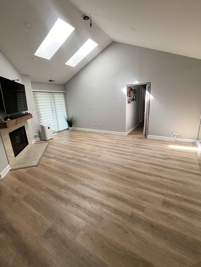 985 W Ct Unit D, Naperville, IL 60563 - unfurnished living room featuring a skylight, vaulted ceiling, a glass covered fireplace, wood finished floors, and baseboards