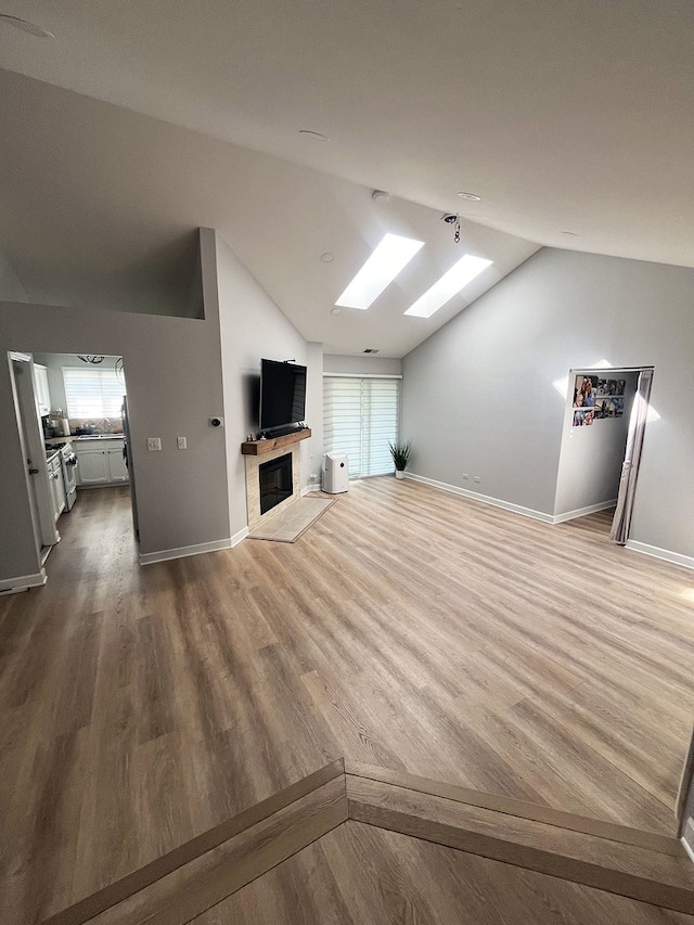 985 W Ct Unit D, Naperville, IL 60563 - unfurnished living room featuring a skylight, lofted ceiling, dark wood-style flooring, a glass covered fireplace, and plenty of natural light