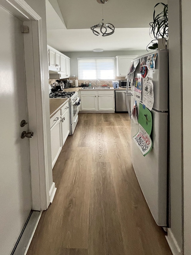 985 W Ct Unit D, Naperville, IL 60563 - kitchen with stainless steel appliances, a sink, wood finished floors, white cabinetry, and light countertops